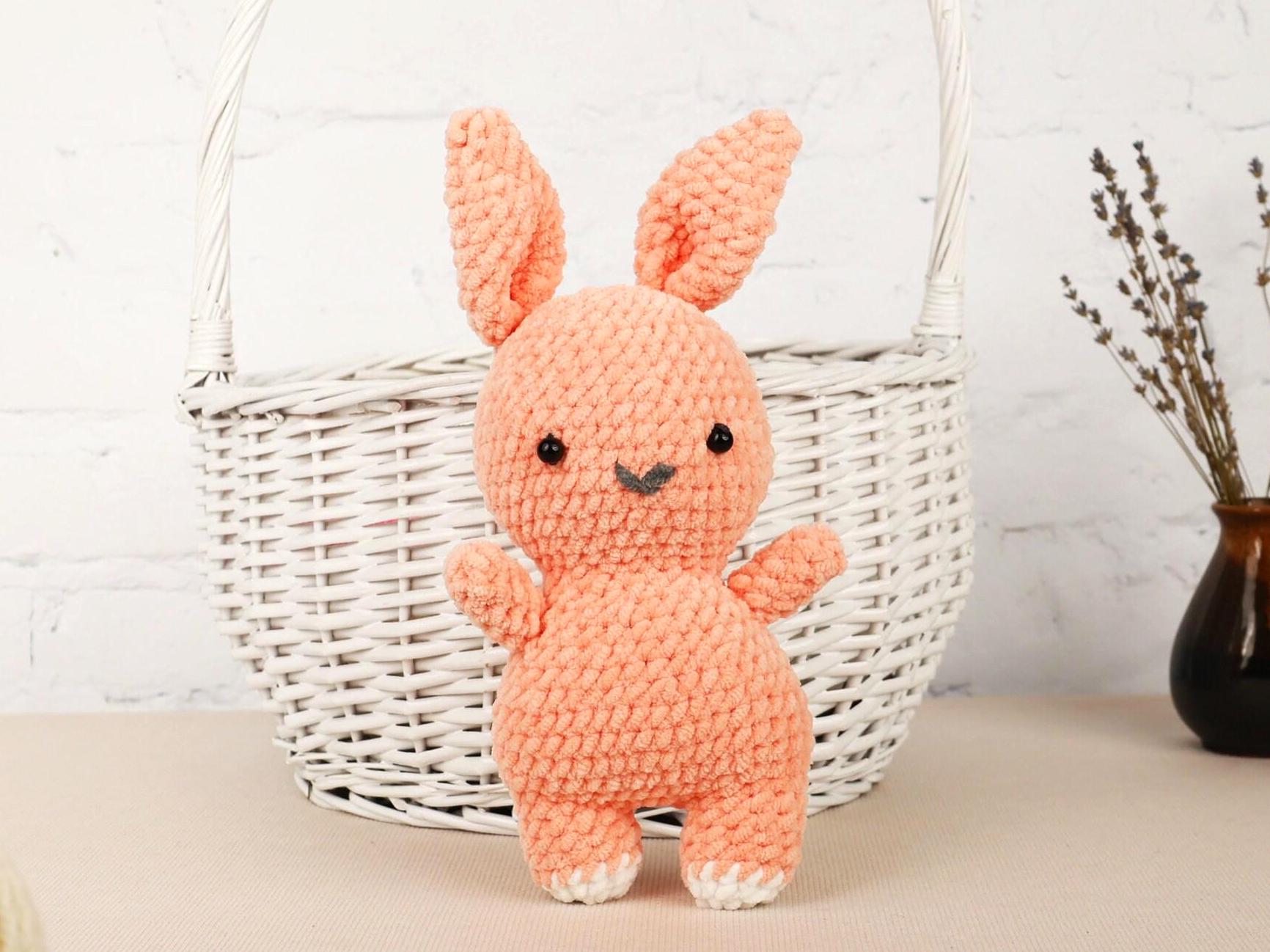 a small crocheted bunny sitting next to a basket